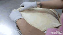 a person wearing gloves is holding a piece of dough in front of a sign that says " made in animotica "