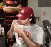 a man wearing a new york yankees hat smoking a cigarette