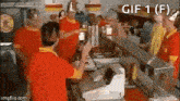 a group of people are standing around a counter in a restaurant .