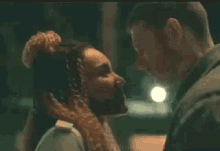 a man and a woman are kissing in front of a street light at night .