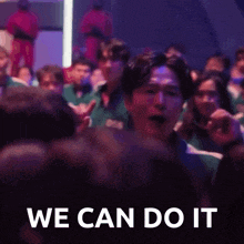 a group of people are sitting in a dark room and a man is screaming in the middle of the crowd .