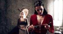 a woman in a red dress is holding a sword