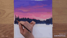 a person is painting a sunset over a lake with trees in the foreground
