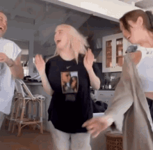 a group of people are standing in a kitchen dancing together .