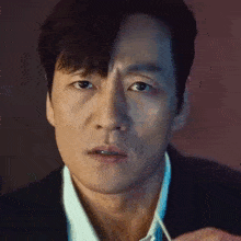 a close up of a man 's face in a suit and tie looking at the camera .