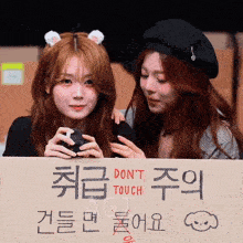 two girls holding a sign that says don 't touch