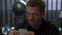 a man in a black shirt is holding a stack of money in his hands