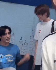two young men are standing next to each other in a room .