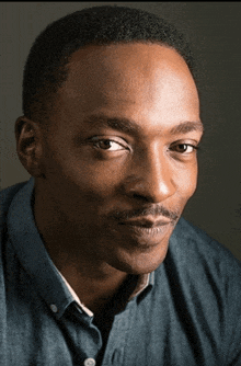 a close up of a man 's face with a denim shirt on