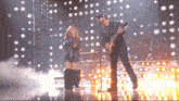 a man is playing a guitar and a woman is singing into a microphone