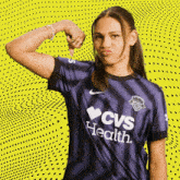 a woman wearing a cvs health shirt flexes her muscles