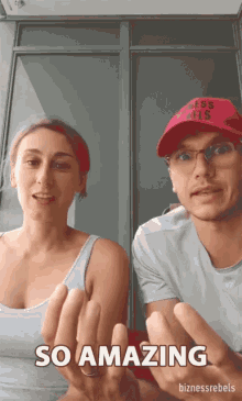 a man wearing a red hat that says ' ness rebels ' on it stands next to a woman