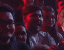 a group of people are sitting in a dark room watching a show .