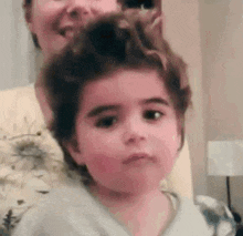 a little girl is sitting next to a woman in a chair with her hair in a bun .