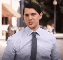 a man wearing a blue shirt and tie is making a funny face .