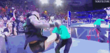 a wrestler is kicking another wrestler in the face during a match .