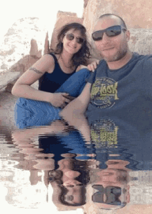a man wearing a top toss shirt sits next to a woman sitting on his lap