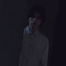 a man in a blue shirt is standing in a dark room