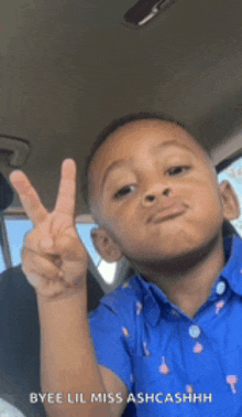 a young boy giving a peace sign in a car