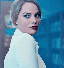 a woman wearing a white shirt and red lipstick is looking at the camera