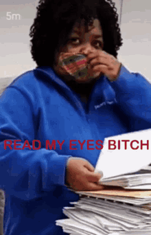 a woman wearing a mask holds a stack of papers with the words read my eyes bitch in red