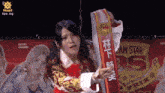 a woman is holding a sash that says rs on it