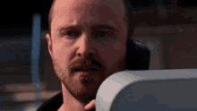 a close up of a man with a beard talking on a cell phone .