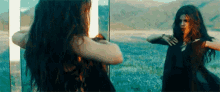 a woman is standing in front of a mirror and looking at herself .