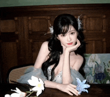 a woman in a dress is sitting at a table with flowers in her hair
