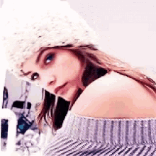 a woman wearing a white hat and a striped sweater is looking at the camera .