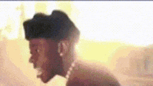 a man with a beard wearing a hat is standing in front of a yellow background .