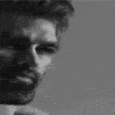 a black and white photo of a man with a beard and glasses .