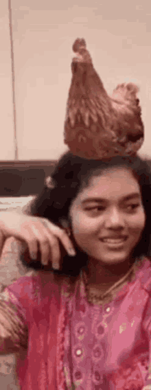 a girl with a chicken on her head is smiling .