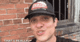 a man wearing a gameday hat says that 's really in front of a brick wall