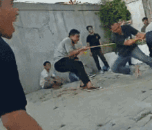 a group of men are playing tug of war on a sandy beach