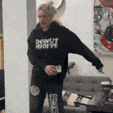a woman wearing a black hoodie that says donut shoppe