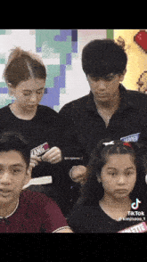 a group of young people are sitting in a room and one of them is wearing a shirt that says yang on it .