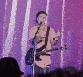 a man playing a guitar and singing into a microphone with a shirt that says thing