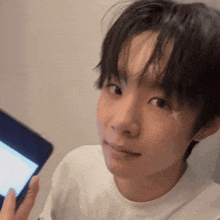 a young man is holding a cell phone in his hand and looking at the camera .