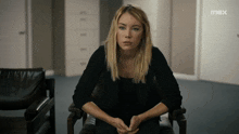 a woman sits in a chair in front of a wall that has the word max on it