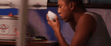 a man is drinking from a white cup in front of a rice cooker
