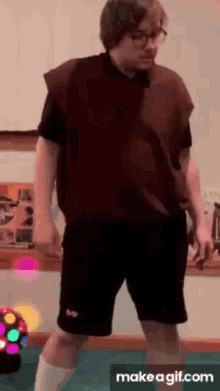 a man in a vest and shorts is dancing in a room .