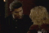 a man and a woman are looking at each other in a dark room .