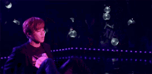a man is sitting on the floor on a stage in front of a purple background .