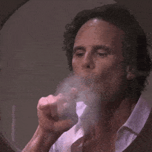 a man in a white shirt is smoking a cigarette
