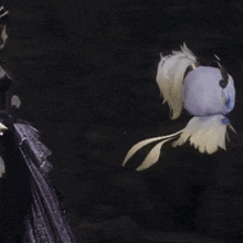 a woman in a purple dress is standing next to a bird with feathers on it .