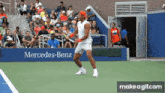 a man playing tennis in front of a mercedes-benz sign