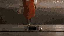 a little girl in a red dress is standing next to a metal briefcase .