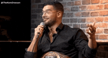 a man in a black shirt is talking into a microphone with the hashtag thekamdreesen on the bottom right