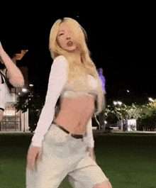 a woman in a crop top and shorts is dancing in a park .